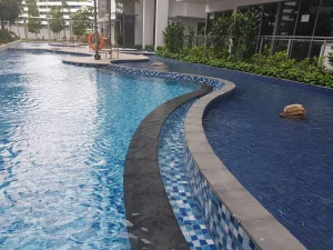 Curved swimming pool with dark stone coping and blue mosaic tiles